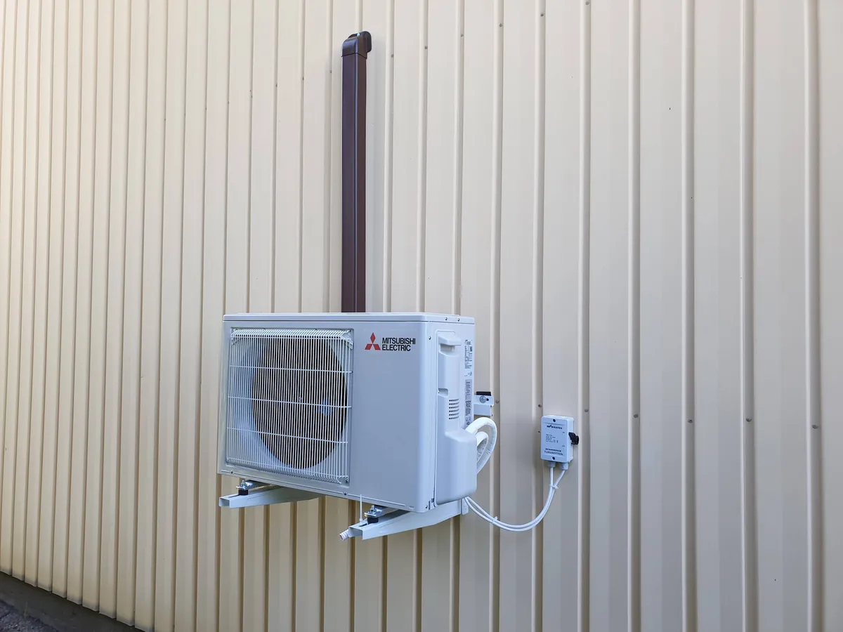 Mitsubishi Electric -ulkoyksikkö seinätelineellä vaalealla peltiseinällä